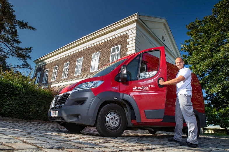 Das Foto zeigt einen Mitarbeiter der Abteilung Tierservice der ebswien kläranlage & tierservice Ges.m.b.H., der stehend die Tür eines Einsatzfahrzeuges (roter Kastenwagen) öffnet. Im Hintergrund ist das Verwaltungsgebäude der Abteilung Tierservice zu sehen. © Christian Houdek